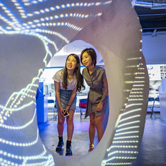 Two female students looking through a model with projections on it