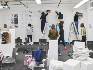 Students standing on ladder to pin up their work on the walls