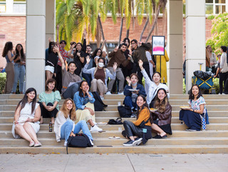A group of students sitting on steps outside in a courtyard