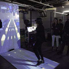 A woman with a VR headset in front of a screen projecting an immersive experience
