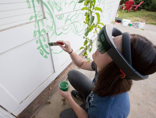 Image of a woman using a VR tool to paint a mural on a wall