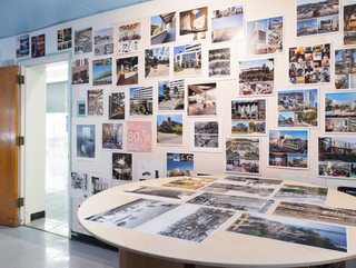 A photograph showing a series of architectural images, each on a square page, assembled across a wall like pixels