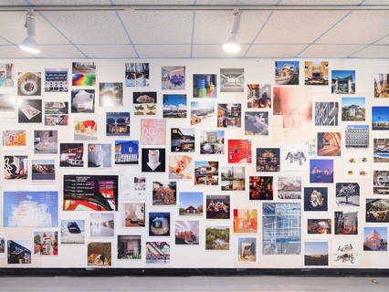 A photograph showing a series of architectural images, each on a square page, assembled across a wall like pixels