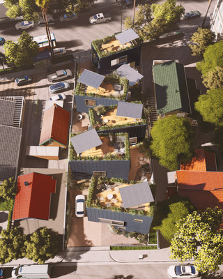 A photo from above showing eight different houses and their roofs on a green hillside with other neighboring houses and a street with cars on it