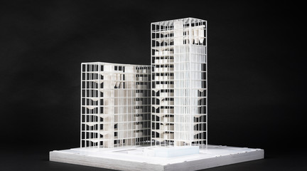 Model of a white high rise building against a black background